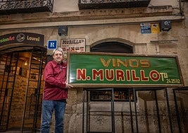 José María Murillo, en la puerta de su local, con un viejo cartel de un antiguo negocio familiar.