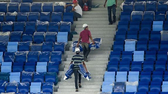 Varios obreros trabajan en un estadio. 