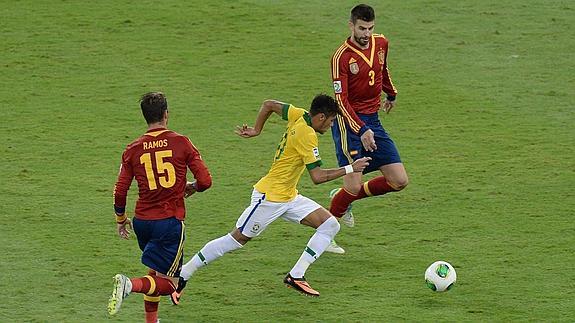 Neymar, en el centro, se marcha de Ramos (i) y Piqué (d).