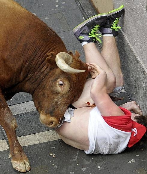 Momento en el que uno de los toros empitona a un mozo. 