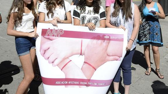 Varias niñas afectadas por la vacuna sostienen una pancarta.
