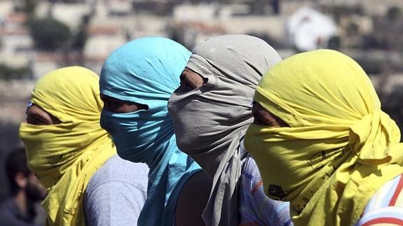 Palestinos enmascarados observan a soldados israelíes durante los enfrentamientos registrados en el asentamiento judío de Qadomem