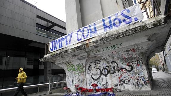 Velas, banderas y flores bajo una pancarta con el lema "Jimmy con nós" (Jimmy con nosotros) colocada en el exterior del estadio coruñés de Riazor. 