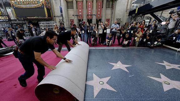 Operarios despliegan la alfombra roja. 