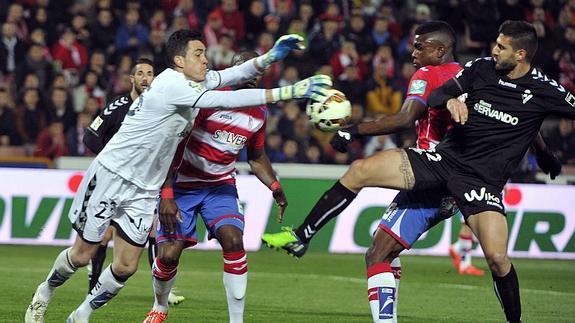 El guardameta del Eibar, Jaime (i), intenta despejar un balón ante el delantero mexicano del Granada, John Andrés Córdoba (2d) y su compañero, Raúl Rodríguez Navas. 