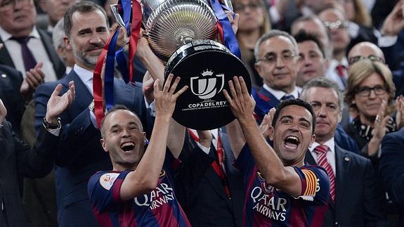 Iniesta (i) y Xavi levantan el trofeo. 