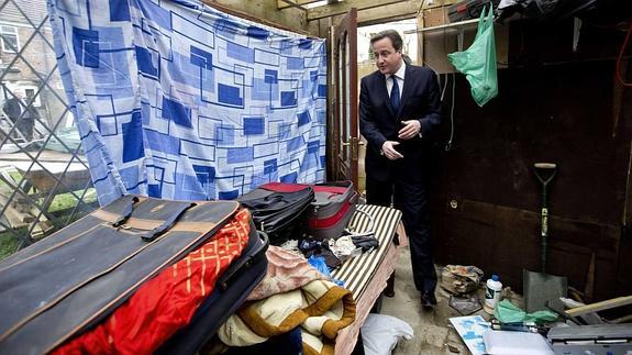 David Cameron, en visita a una caseta en el barrio londinense de Southall donde la policía descubrió inmigrantes ilegales.