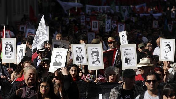 Manifestantes portan retratos de víctimas de la dictadura de Pinochet.