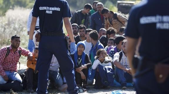 Policías húngaros vigilan a refugiados que han cruzado la frontera con Croacia. 