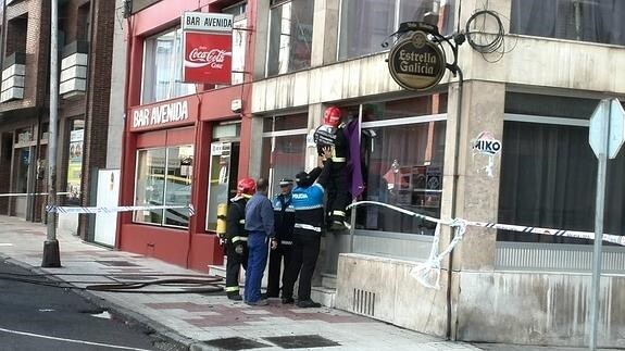Los bomberos, ayudados por la Policía Local, tratan de acceder al bar.