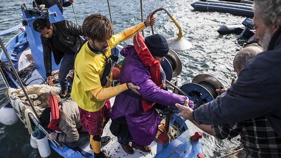 Un cooperante ayuda a desembarcar a un grupo de refugiados que trataban de llegar a Lesbos. 