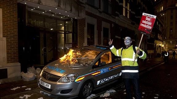 Un vehículo de la policía es atacado por manifestantes.