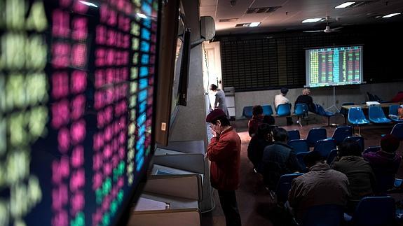 Un grupo de analistas chinos observan indicadores bursátiles.