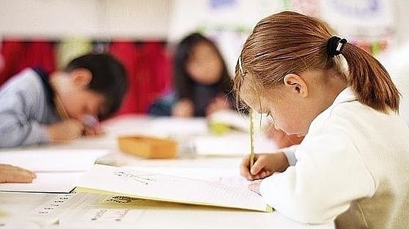 Una niña escribe en clase. 