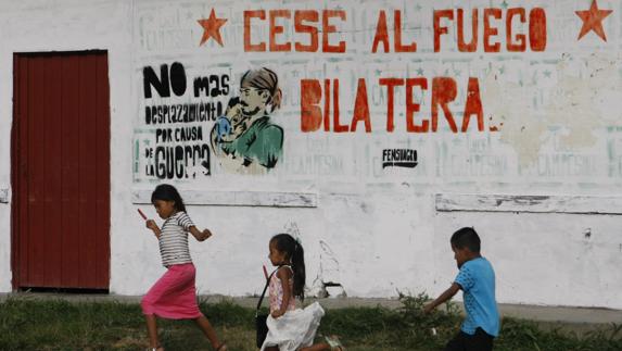 Tres niños pasan ante un mural alusivo al alto el fuego en El Paulo, Cauca (Colombia).