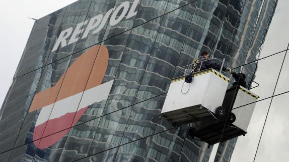 Un limpiacristales abrillanta la fachada de la sede de Repsol, en Madrid.