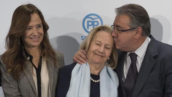 El ministro del Interior, Juan Ignacio Zoido, besa a la madre del que fuera concejal popular del Ayuntamiento de Sevilla Alberto Jiménez Becerril, Teresa Barrio (c), junto a la hermana del mismo, María Teresa.