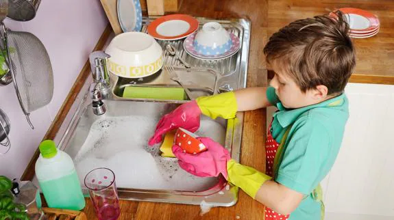 Un niño lavando los platos.