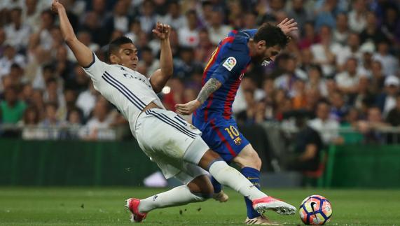 Casemiro disputa un balón con Leo Messi. 
