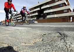 Dos ciclistas circulan pedaleando por una carretera con baches de los alrededores de Logroño./J.R.