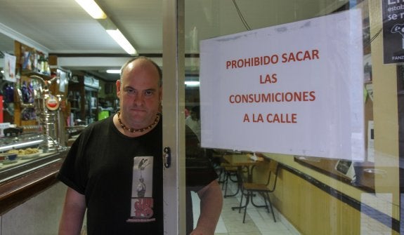 El propietario del Bar Iturza junto al bien visible cartel de 'Prohibido sacar las consumiciones a la calle'. 