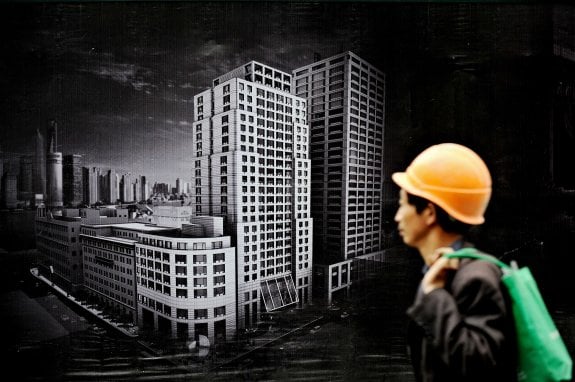Un trabajador camina junto al cartel de una nueva promoción inmobiliaria en Shanghái. :: PHILIPPE LOPEZ / afp