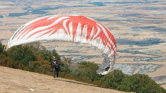 Un hombre intenta iniciar el vuelo en parapente sobre una montaña.