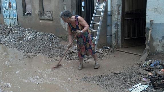 Una señora trata de limpiar la casa y el acceso. 