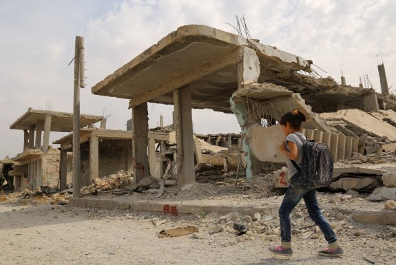 Una niña se dirige al colegio a través de las ruinas de la ciudad siria de Kobani, que los kurdos consiguieron arrebatar al EI. :: D. SOULEIMAN/ afp