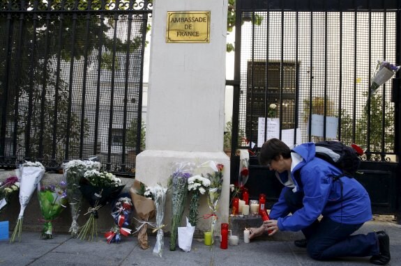 Una mujer deposita una vela blanca junto a la Embajada de Francia en Madrid. :: Sergio Pérez / reuters
