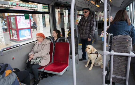 Alfonso Muñoz, ayer con su perro guía, en el autobús que coge cada día para desplazarse por la ciudad. :: SONIA TERCERO