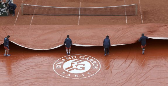 Los operarios cubren una de las pistas de Roland Garros por la lluvia. :: reuters