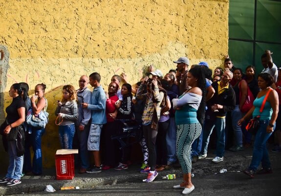 Un grupo de gente hace cola a las puertas de un supermercado de Caracas para comprar alimentos. :: RONALDO SCHEMIDT / afp