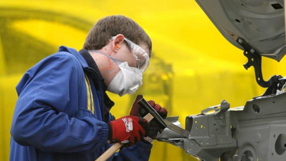 Un joven especialista en chapa trabaja en una competición de automoción. 