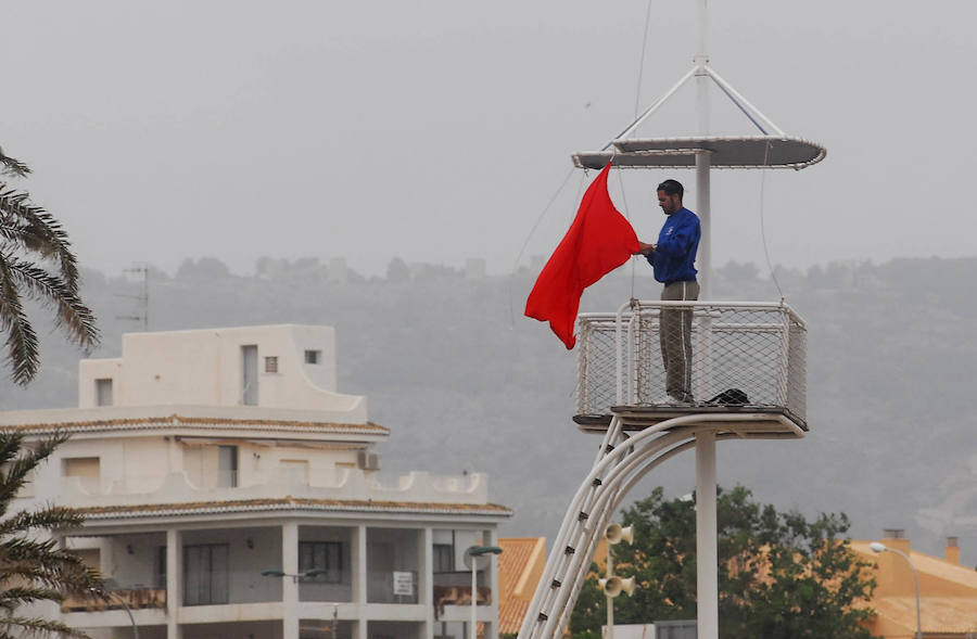 Un socorrista iza la bandera roja en una playa del levante español. 