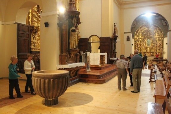 La pila bautismal, en primer plano; al fondo, el retablo de la patrona restaurado. ::
