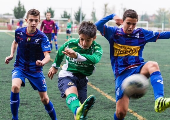 Dos jugadores del Comillas tratan de obstaculizar el golpeo de un futbolista del Berceo. :: F. díaz