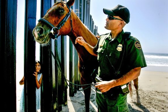 Una niña mejicana observa a un agente de la guardia fronteriza en California. :: afp