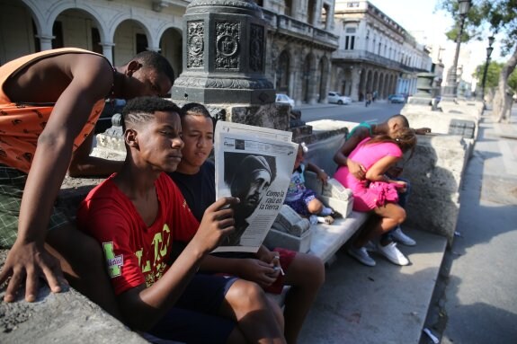 Varios jóvenes de La Habana leen la información sobre el sepelio de Fidel Castro en el diario 'Granma'. :: Luis Ángel Gómez