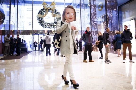 Una mujer camina por el vestíbulo de la Torre Trump en Nueva York con una careta de Hillary Clinton. :: Justin Lane / efe