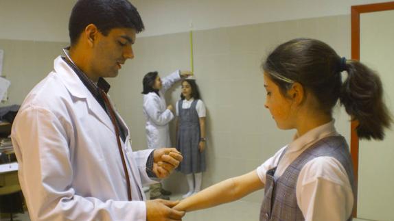 Un médico toma el pulso a una niña en un reconocimiento médico. 