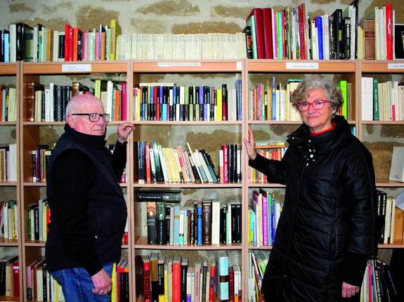 Jesús y Adelina posan junto a una de las estanterías de la biblioteca. 