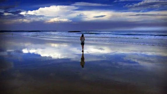 Una mujer contemplando el bello paisaje en la playa de Mollymook. 