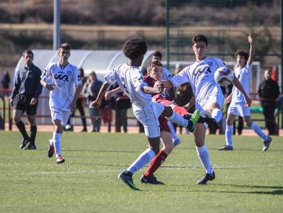 Un jugador cadete del EDF trata de llevarse el balón rodeado de contrarios. :: Fernando Díaz