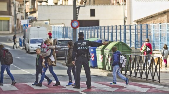 Un agente de la Policía Local de Lardero facilita el cruce de la calle por los escolares de la localidad a su salida del colegio González Gallarza. :: 