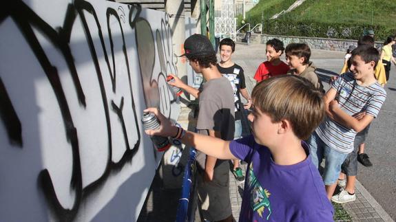 Un grupo de niños pinta un grafiti. 