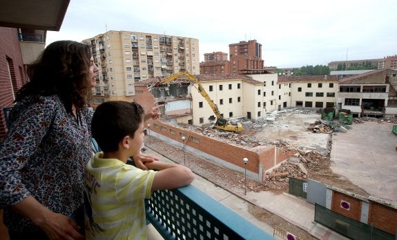 Una vecina de la calle Guipúzcoa observa, junto asu hijo, el avance de las obras del antiguo Paula Montal, centradas ayer en la fachada noroeste. :: 