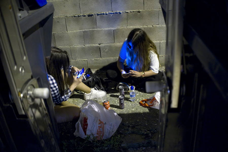 Dos jóvenes, de botellón, mientras se comunican por el móvil. 