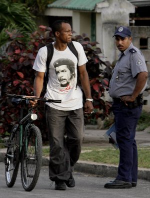 Un habanero pasa con su bici ante un policía. / AP