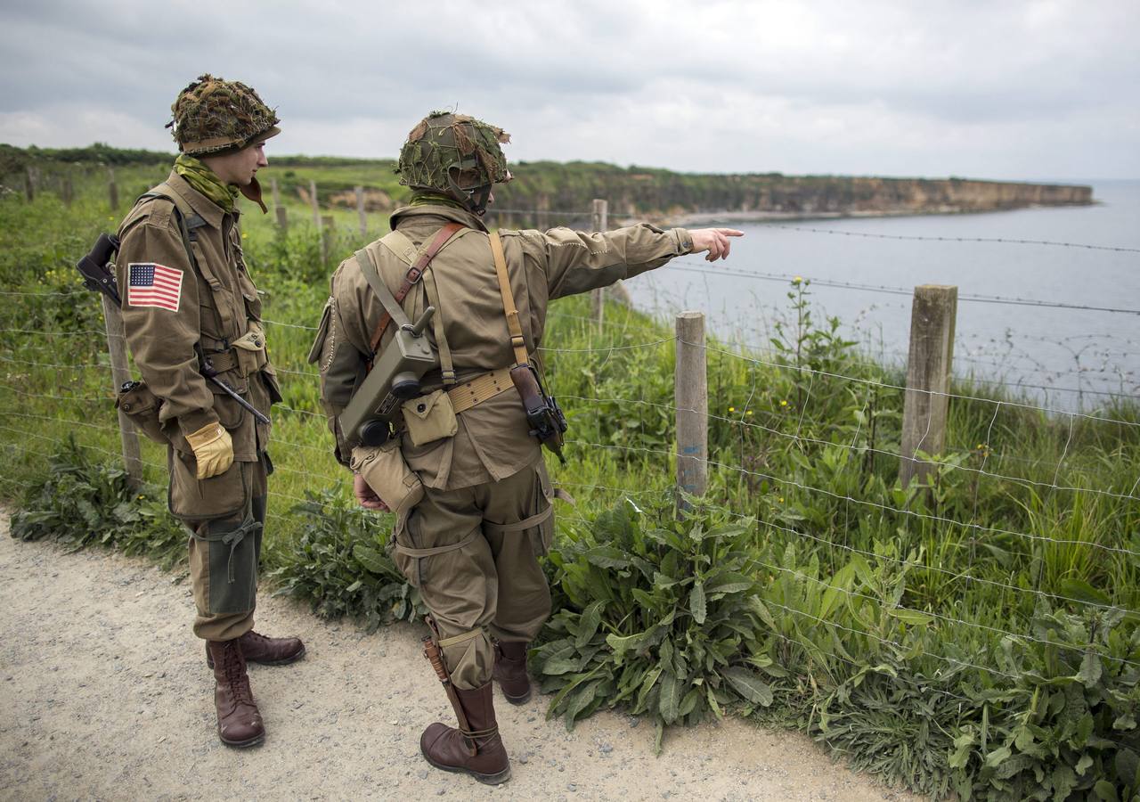 Varios entusiastas de la Segunda Guerra Mundial, con réplicas de los uniformes militares de la época, observan los acantilados de Pointe du Hoc.